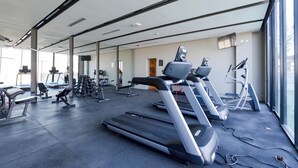 Une salle de sport équipée de tapis de course, de poids et d’autres appareils d’exercice.