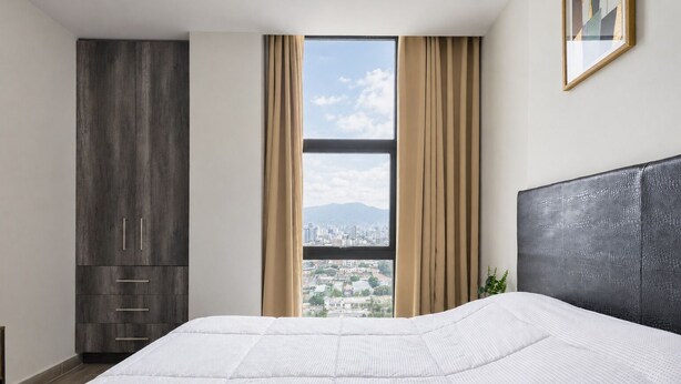 Une chambre avec un grand lit, une armoire, une fenêtre avec des rideaux et une vue sur la ville.