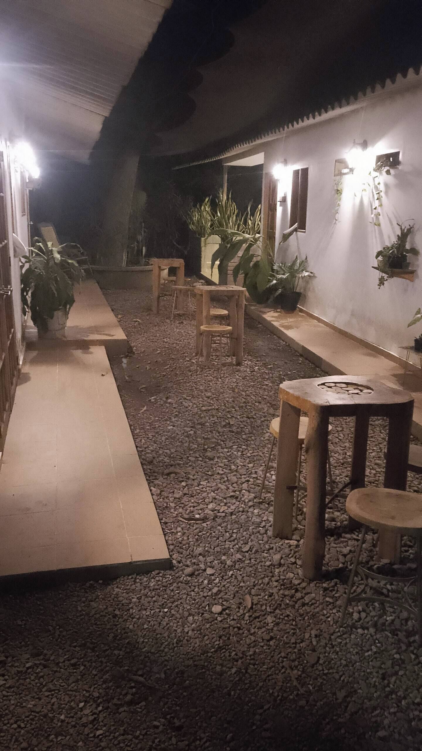 Un patio al aire libre con suelo de grava, bancos de madera y plantas en macetas.
