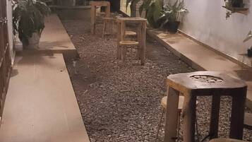 Un patio al aire libre con suelo de grava, bancos de madera y plantas en macetas.