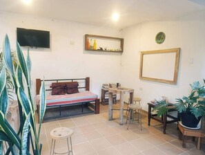 A compact room with a bed, a television, a mirror, and a small table. - Avocado: Harmony, Texture, Connection, and Peace 187715 (Palomino)