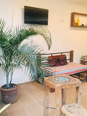 A bedroom with a bed, a television, a small table, and a potted plant.