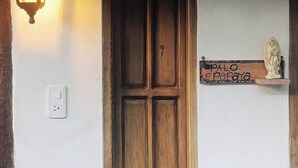 Uma porta com moldura de madeira, um candeeiro fixado na parede e um pequeno prateleira com uma estátua.
