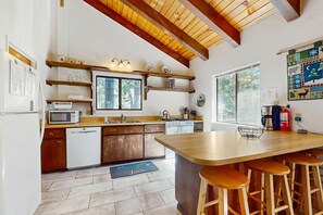 Eine Küche mit Holzausstattung, einer Mikrowelle, einem Spülbecken und einer Bar mit Hockern.