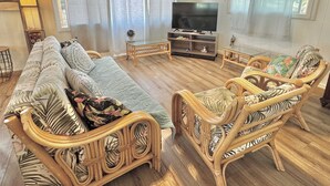 Una sala de estar con un sofá, dos sillones, un televisor y una mesa de centro de madera.