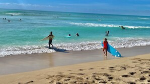 Una playa con gente surfeando y caminando por la orilla.