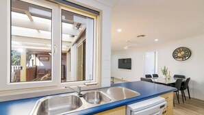 Cocina moderna con encimera azul, pileta de acero inoxidable y lavavajillas.