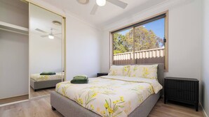 Un dormitorio con cama, radiador, ventana con vistas y ventilador de techo.