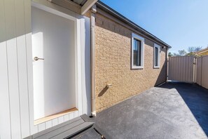 A building with a white door, a window, and a concrete patio area. - The Sunroom Guesthouse by Esteem Retreats (Stanhope Gardens)