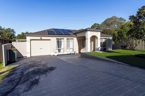 Um imóvel residencial com garagem, painéis solares, gramado e cerca.