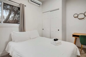A bedroom with a bed, a window with curtains, a wardrobe, a desk, and a wall-mounted circular decoration. - Private Boise Bench Retreat (Boise)