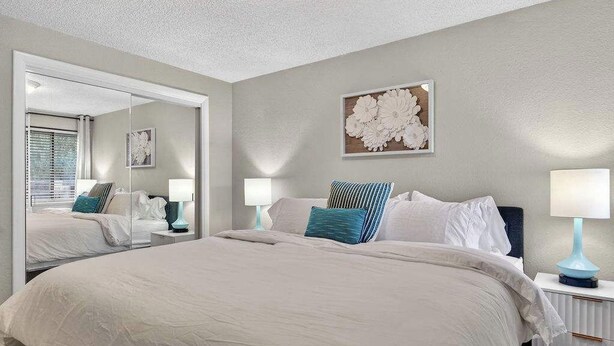 A bedroom with a large bed, a mirror, a wall-mounted artwork, and bedside lamps. - 24th St Hideaway - Pet Friendly North End Retreat (Boise)