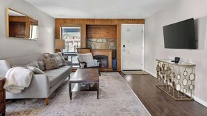 A modern living room with a sofa, coffee table, fireplace, and a TV mounted on the wall. - 24th St Hideaway - Pet Friendly North End Retreat (Boise)