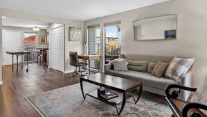 A living room with a sofa, coffee table, and a dining area with a table and chairs. - 24th St Hideaway - Pet Friendly North End Retreat (Boise)