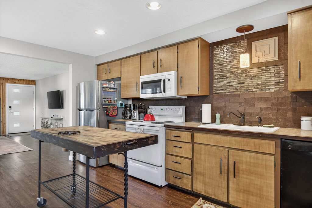 Una cocina moderna con armarios de madera, electrodomésticos de acero inoxidable y una isla central.