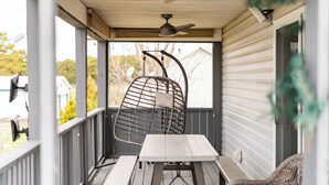 Eine überdachte Veranda mit Tisch und Stühlen, einem Deckenventilator und Blick ins Viertel.