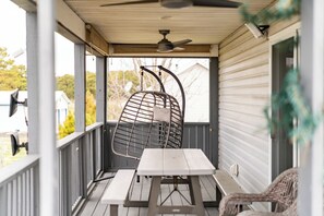 Eine überdachte Veranda mit Tisch und Stühlen, einem Deckenventilator und Blick ins Viertel.