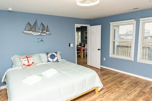 Ein Schlafzimmer mit einem Bett, einer Wand mit Segelbooten und einer Tür zu einem weiteren Raum.