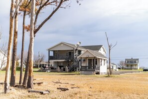 Ein zweistöckiges Haus mit Veranda, Satellitenschüsseln und einem umzäunten Garten.
