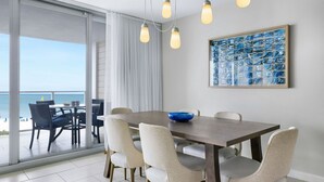 A dining area with a table, chairs, a bowl, and a view of the ocean through large windows. - CRYSTAL SHORES MARRIOTT exclusive!! (Marco Island)
