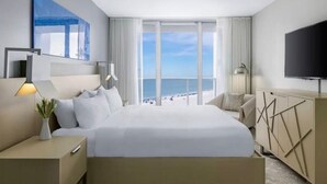 A hotel room with a large bed, a TV, a desk with a lamp, and a view of the beach. - CRYSTAL SHORES MARRIOTT exclusive!! (Marco Island)