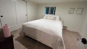 Ein Schlafzimmer mit Bett, Fenster, Tür und Kommode.