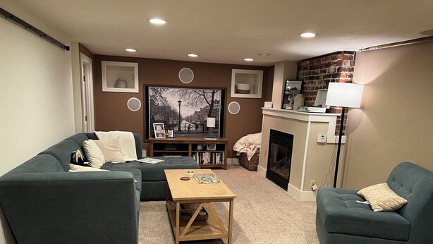 Ein Wohnzimmer mit einer Eckcouch, einem Couchtisch, einem Kamin und einem Bücherregal.