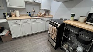 Eine moderne Küche mit weißen Schränken, einem Edelstahlherd und einer Holz Arbeitsplatte.