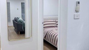 Una habitación con cama, espejo, teléfono y cubo de basura.