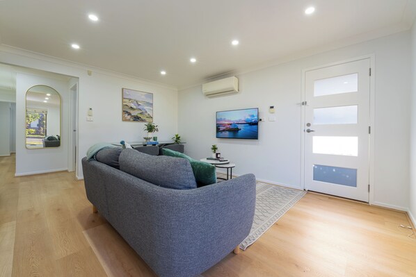 A modern living room with a grey sofa, a small side table, and a painting on the wall.
