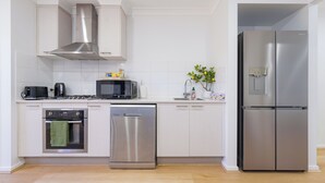 Una cocina moderna con electrodomésticos de acero inoxidable, incluyendo un microondas, horno, lavavajillas y refrigerador.