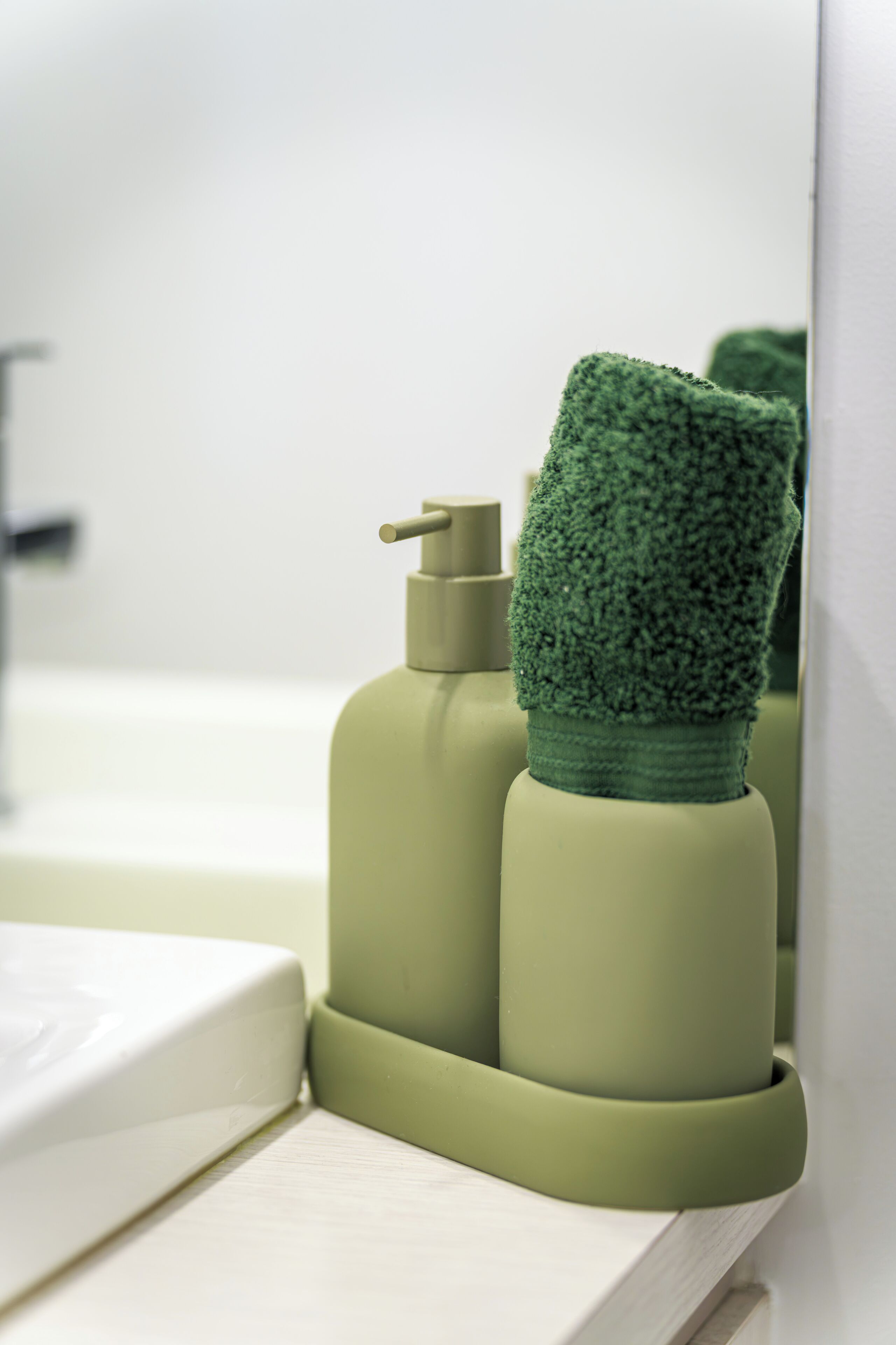 Une salle de bain avec un distributeur de serviettes vertes et un lavabo blanc.