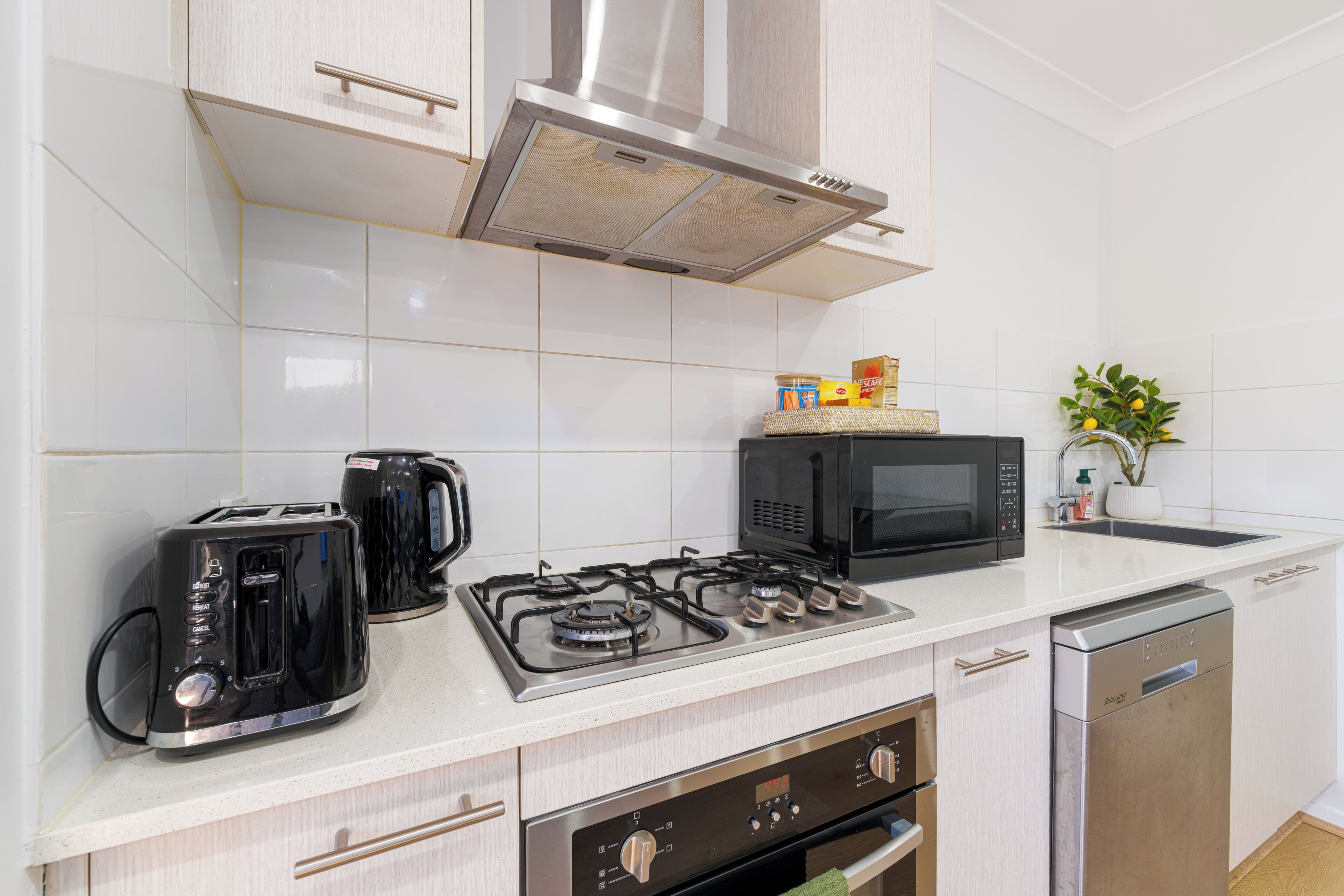 A modern kitchen with a gas stove, a microwave, a toaster, and a coffee maker.