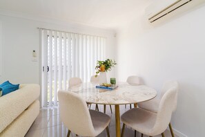 Een moderne eethoek met een ronde tafel, vier stoelen en een potplant.
