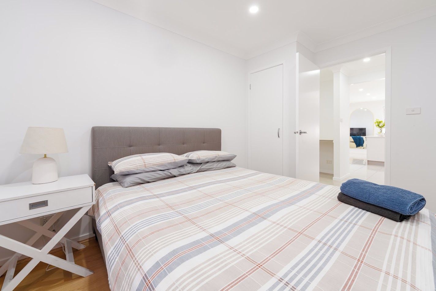 Une chambre à coucher avec un lit, une table de chevet, une lampe et une serviette bleue.