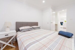 Une chambre à coucher avec un lit, une table de chevet, une lampe et une serviette bleue.