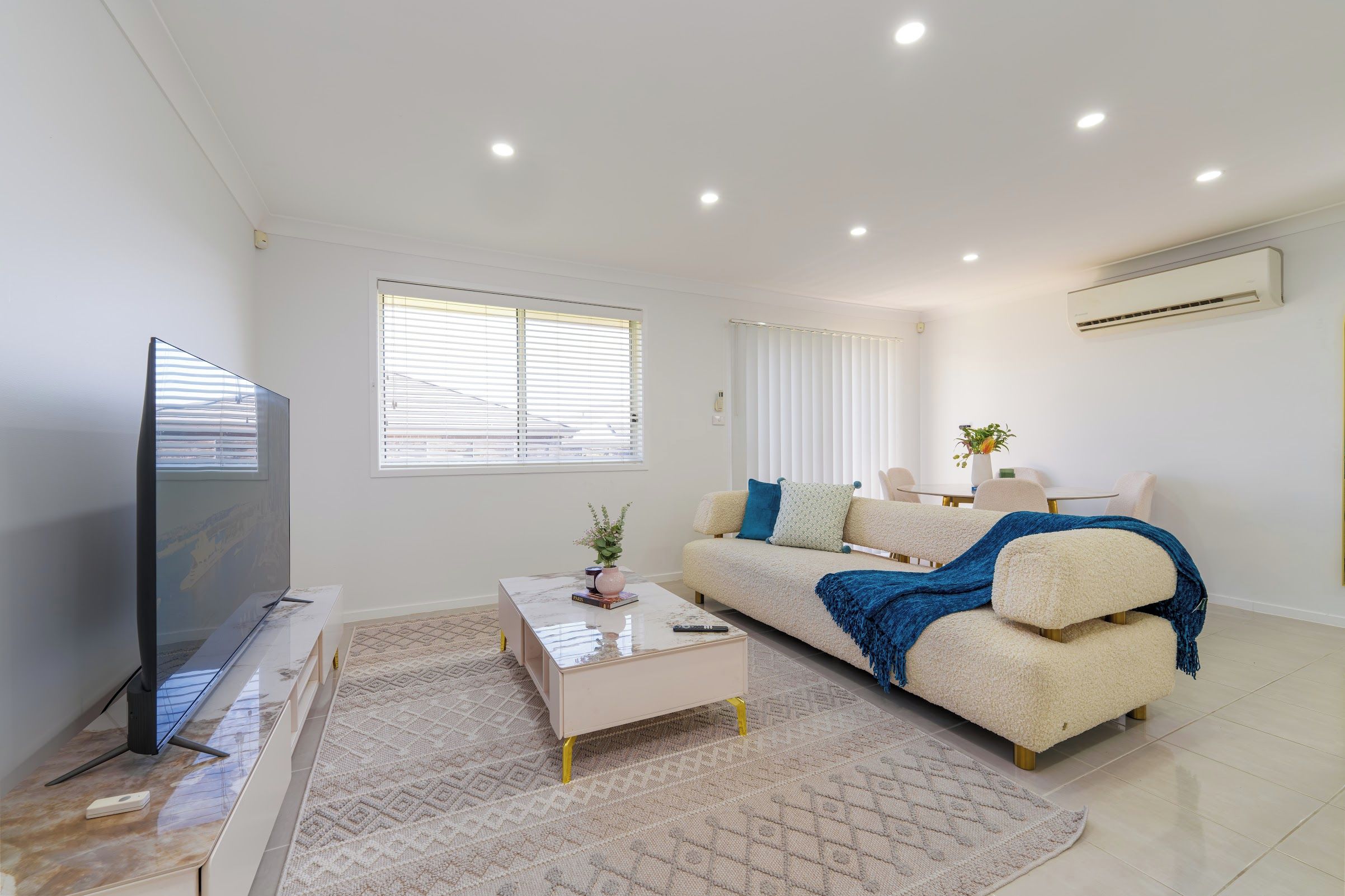 A modern living room with a flat-screen TV, a sofa with a throw blanket, and a coffee table.