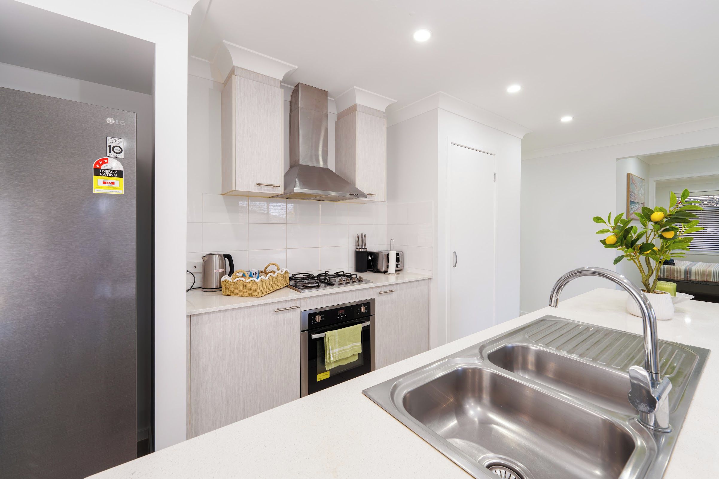 A modern kitchen with a stainless steel refrigerator, a gas stove, and a double sink.