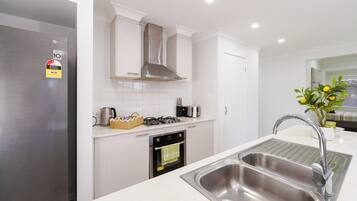 A modern kitchen with a stainless steel refrigerator, a gas stove, and a double sink.