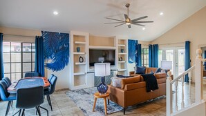 A spacious living area with a dining table, sofas, a TV, and a ceiling fan. - Peoria Resort! Spacious 7BR, Heated Pool, Theater, Hot Tub, Ping Pong & More! (Peoria)