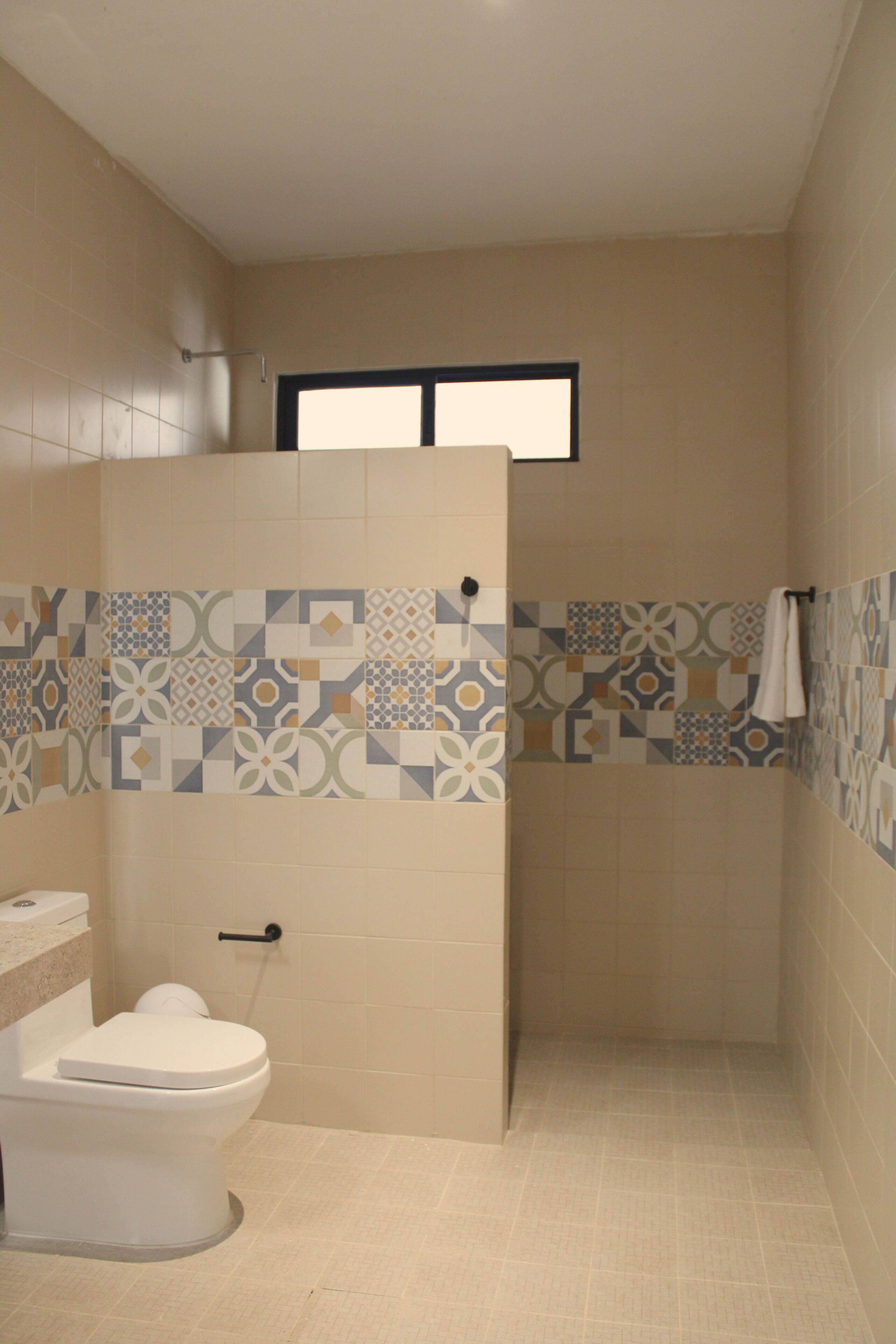 A bathroom with a toilet, a shower, and a window.