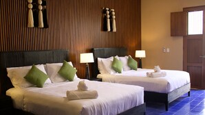 Two double beds with white linens and green pillows, wooden paneling on the walls, and a blue tiled floor. - Casa Ku'x (Merida)