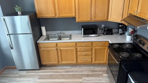 Una cocina con armarios de madera, electrodomésticos de acero inoxidable, un microondas y una estufa.