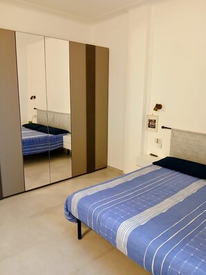 A bedroom with a bed, a wardrobe, and a mirror. - Incantevole vista mare - Mareri apartments (Sanremo)