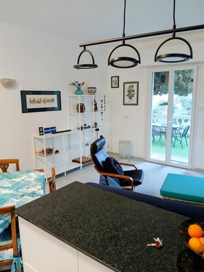 A modern living room with a dining area, a black leather chair, a white shelving unit, and artwork on the walls. - Incantevole vista mare - Mareri apartments (Sanremo)