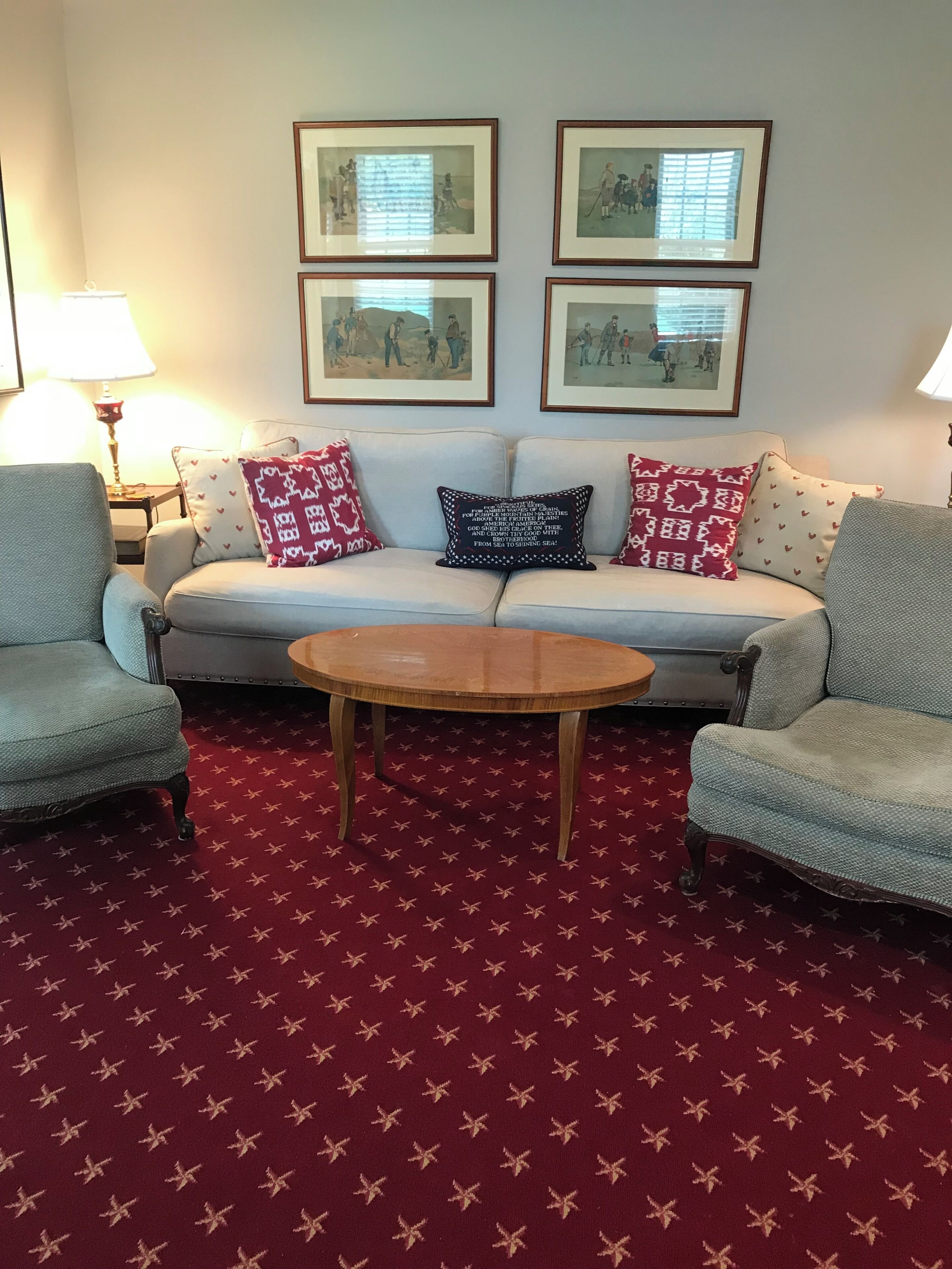 Ein Wohnzimmer mit einer Couch, zwei Sesseln, einem Couchtisch und einem gemusterten Teppich.