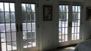 Une chambre avec une grande fenêtre, un lit et un tableau encadré au mur.
