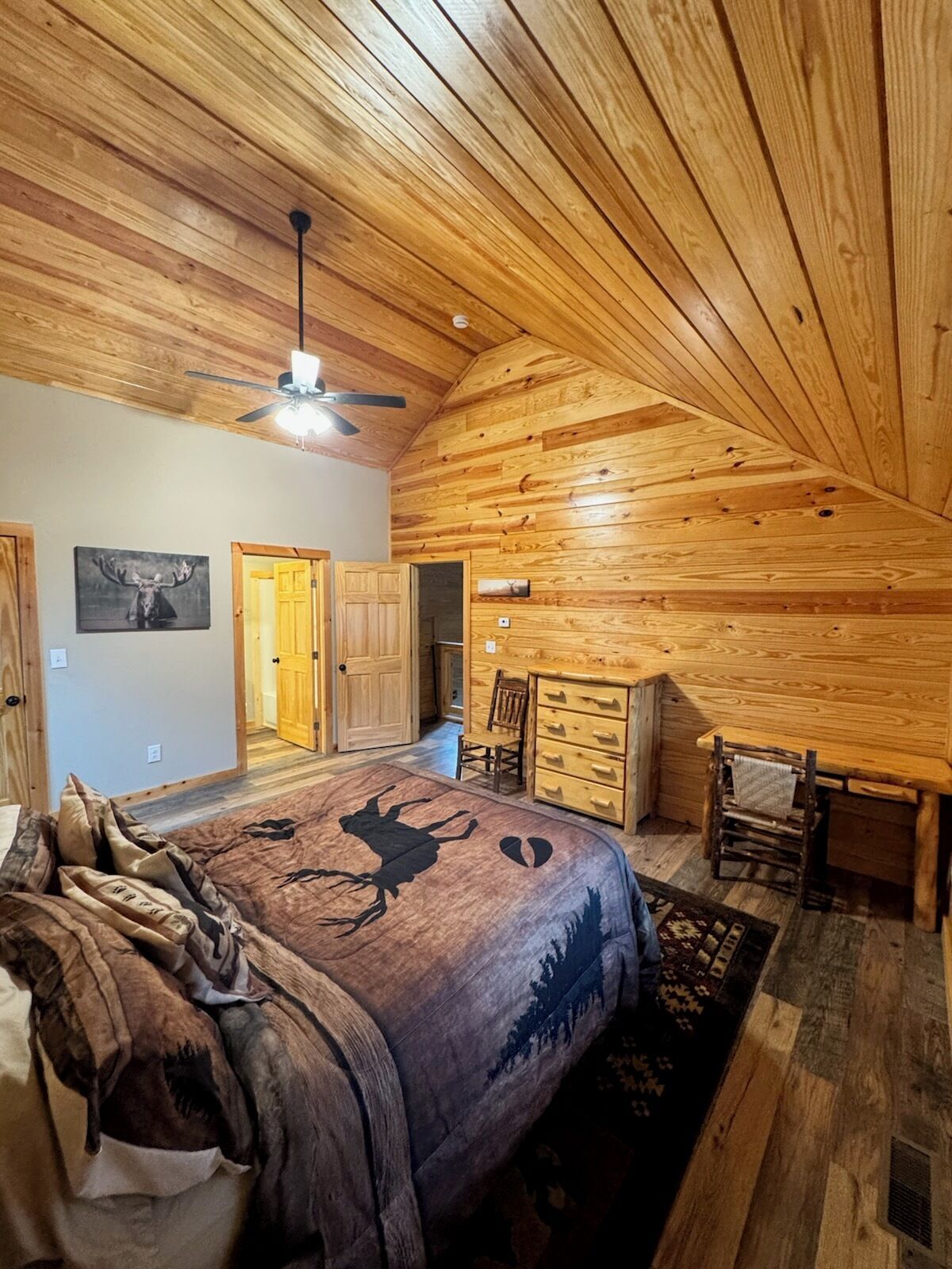 Quarto de cabana de tronco com cama, cômoda e ventilador de teto.