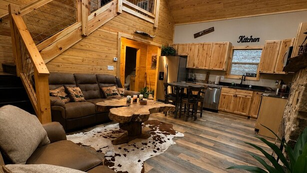 A cozy cabin interior with a living room, kitchen, and a staircase leading to an upper level. - Secluded Cabin + Private Lake Access - No Parkway Traffic - Hidden Ridge Retreat (Sevierville)