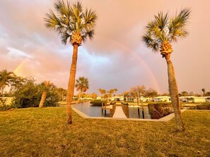 A pool area with palm trees and a view of a building complex. - Fishing paradise! 3BR, 2Bath waterfront home. Walk to beach. Dock & boat lift.  (Nokomis)